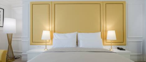 A hotel room with a large bed, two bedside tables, a lamp on each table, and a chair.