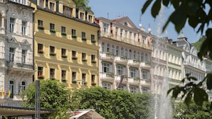 Una hilera de edificios históricos con balcones, una fuente y el letrero de un restaurante.
