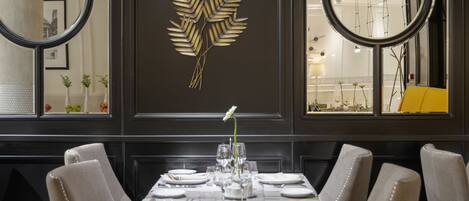 A dining area with a rectangular table set for four, surrounded by upholstered chairs with button detailing.