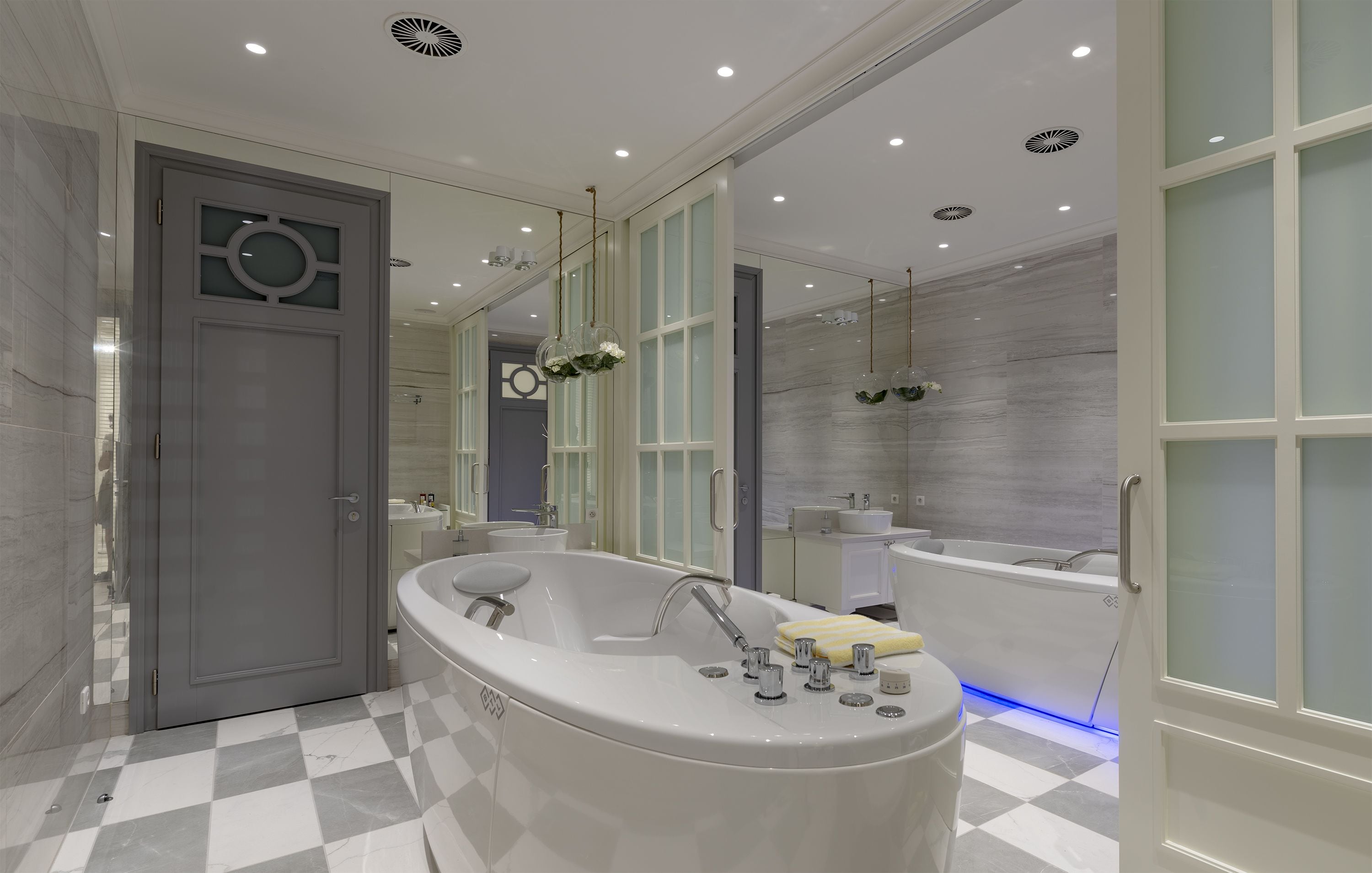 A modern bathroom with a freestanding bathtub, a large mirror, and a checkered floor.