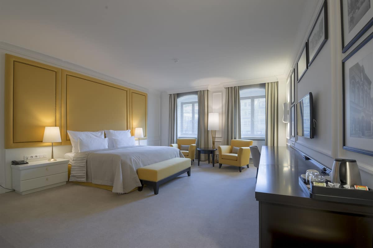Een hotelkamer met een groot bed, nachtkastjes, een bureau, een stoel en een televisie.