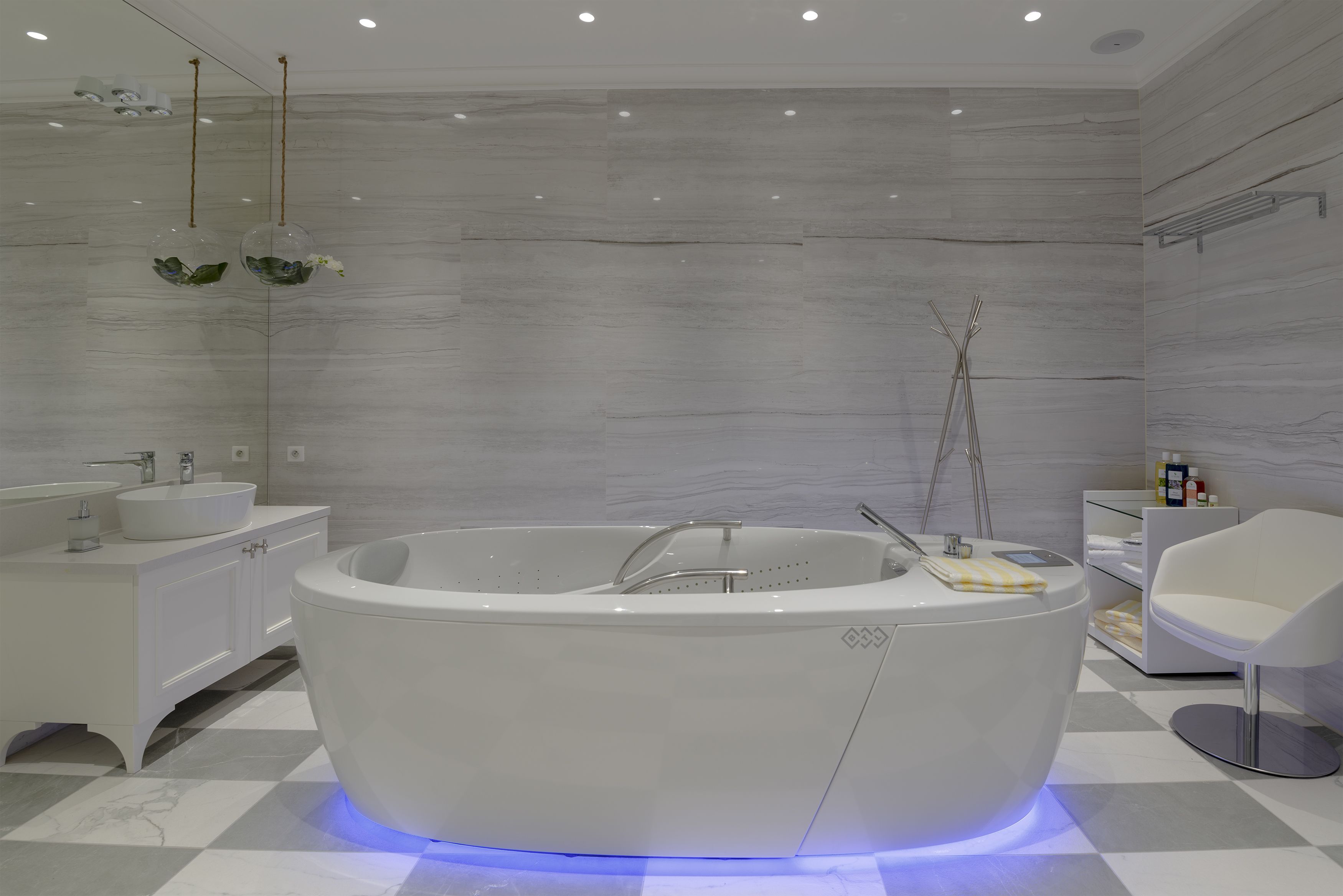 A modern bathroom with a freestanding bathtub, a vanity with a sink, and a chair.