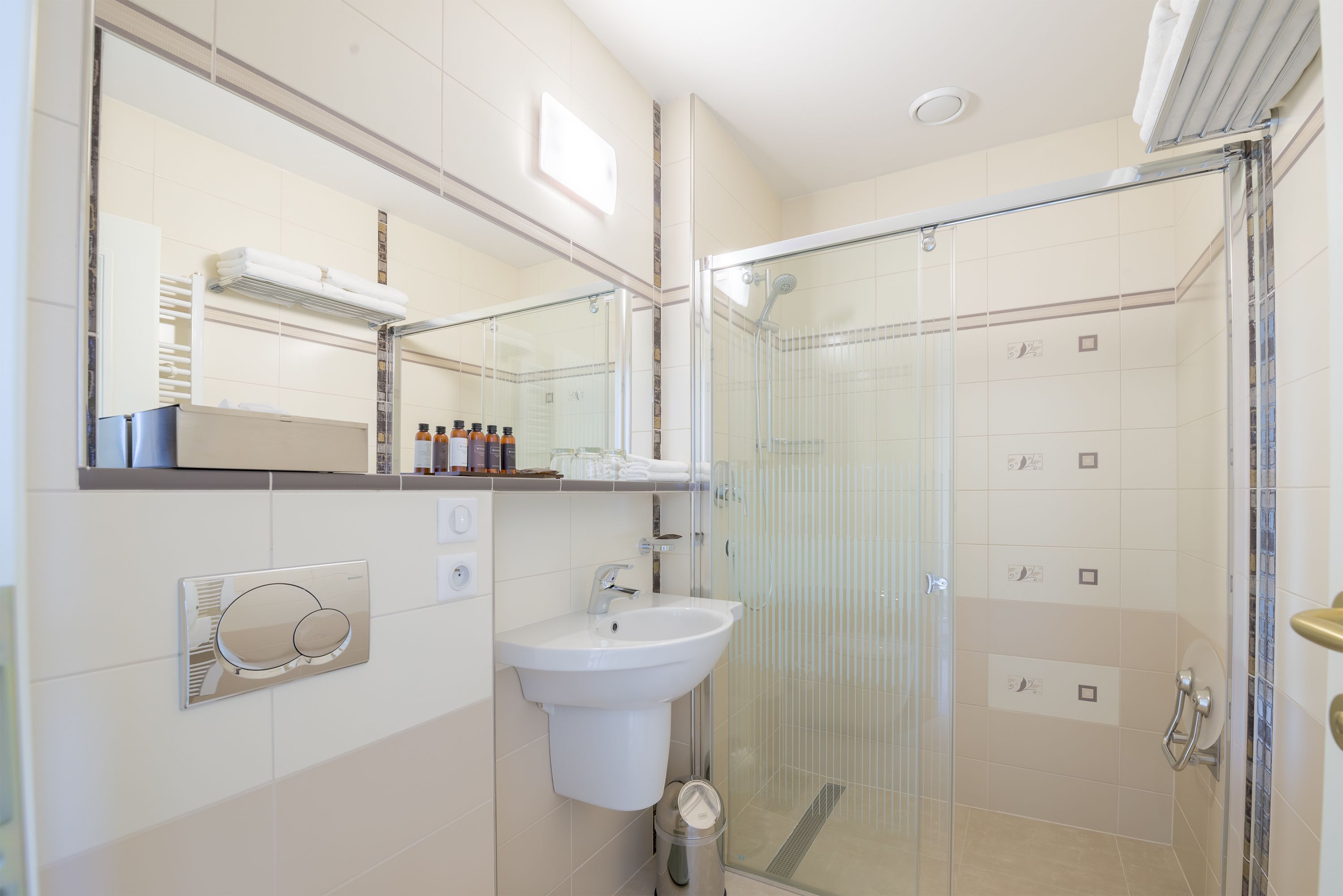 Un baño moderno con ducha envuelta en vidrio, un lavabo blanco y un espejo sobre él.
