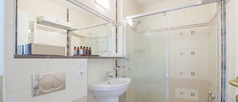 Une salle de bain moderne avec une douche à parois de verre, un lavabo blanc et un miroir au-dessus.