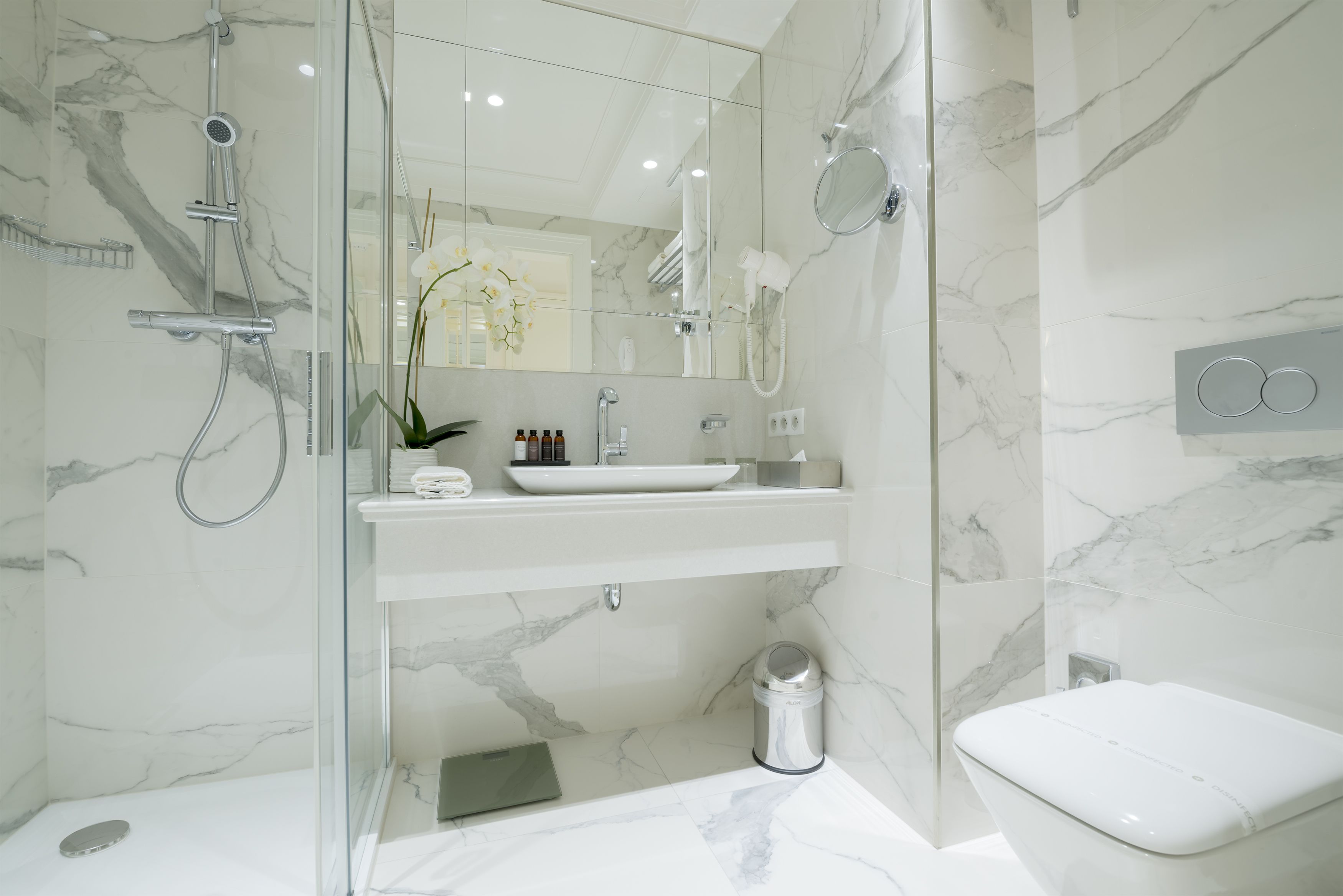 Une salle de bain moderne avec une douche à parois de verre, un lavabo blanc et des toilettes.