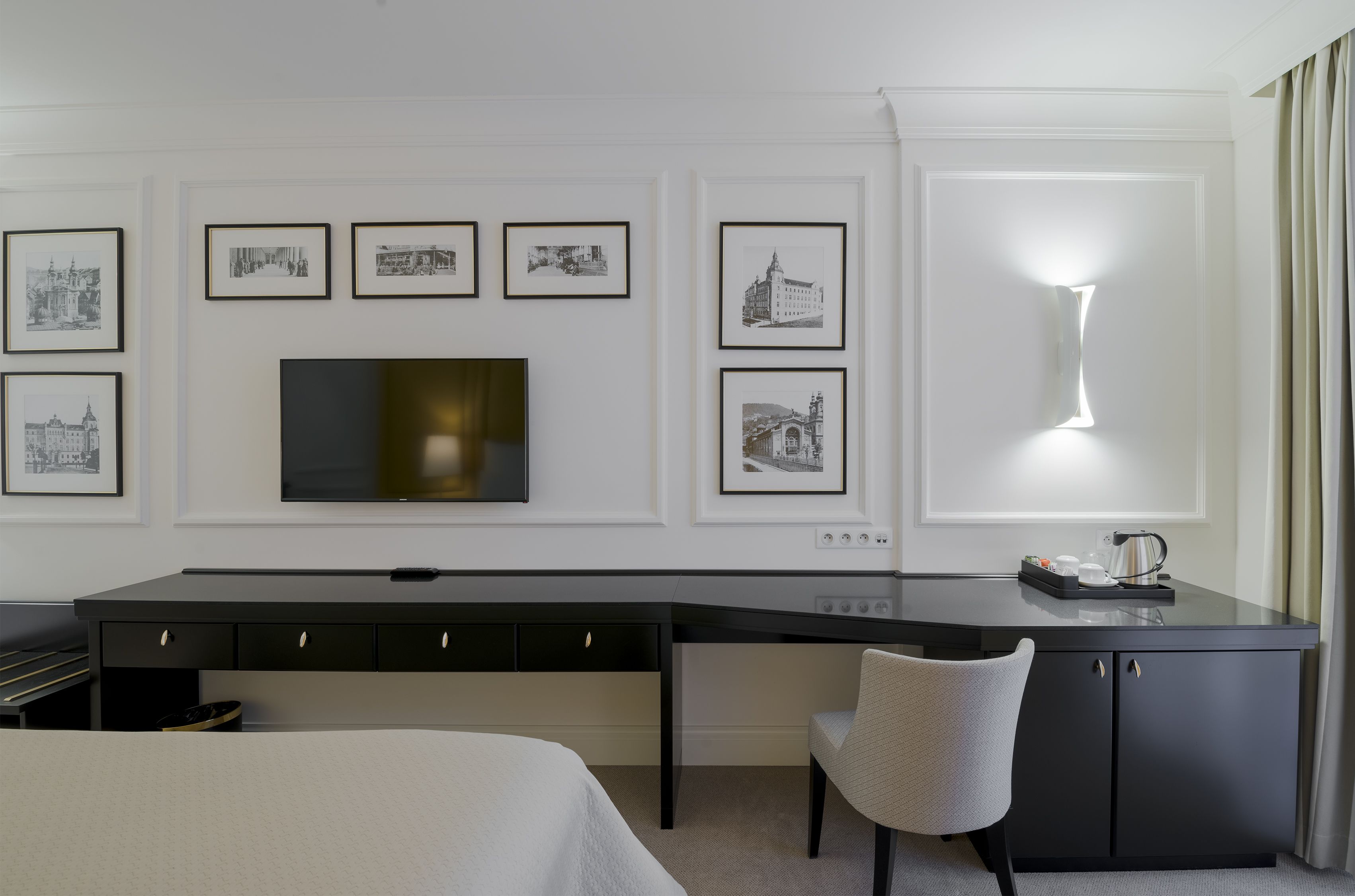 A modern hotel room with a large desk, a flat-screen TV, and a bed.