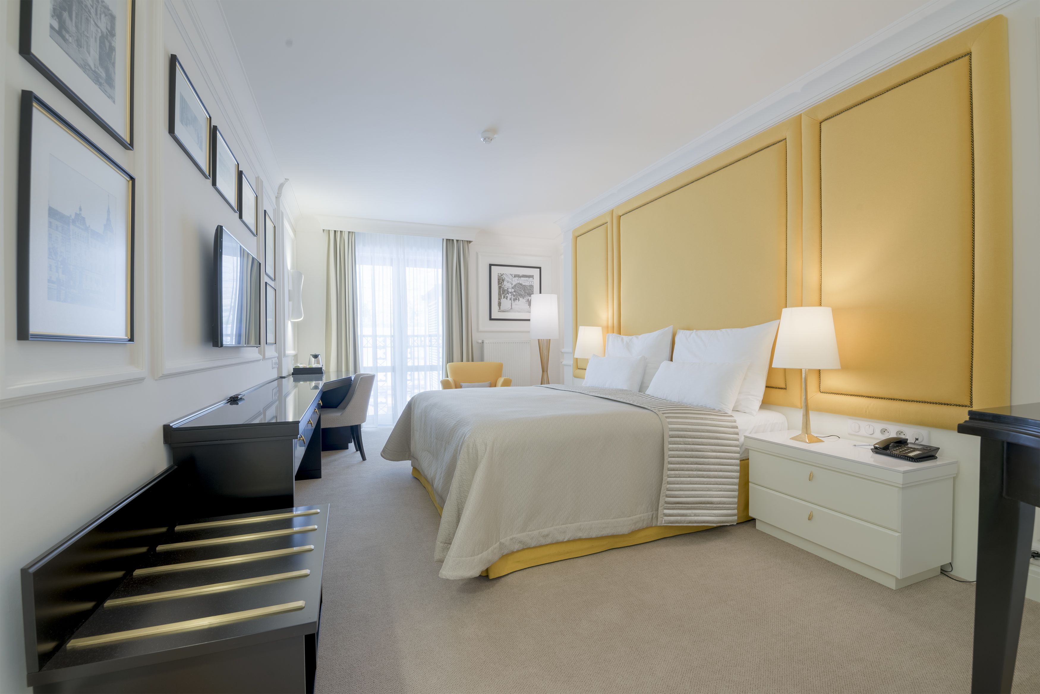 A hotel room with a bed, bedside tables, a desk, and chairs.