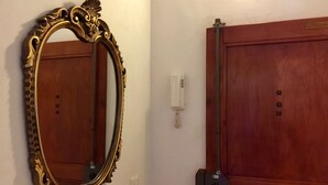 Una habitación con una puerta de madera, un interruptor de luz en la pared y un espejo grande y decorativo.
