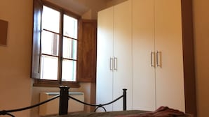 Un dormitorio con cama, ventana, radiador y armario.
