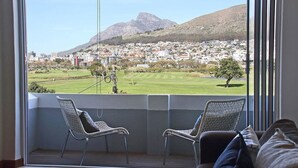 Ein Balkon mit zwei Korbstühlen, Blick auf eine Stadt und Berge, und ein Ausblick auf einen Golfplatz.