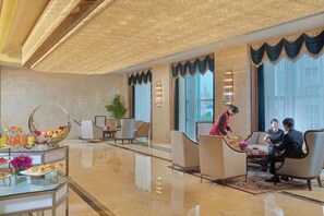 A hotel lobby with a reception desk, seating area, and a large window with a view. - Sanyu Grand New Century Hotel (Wenzhou)