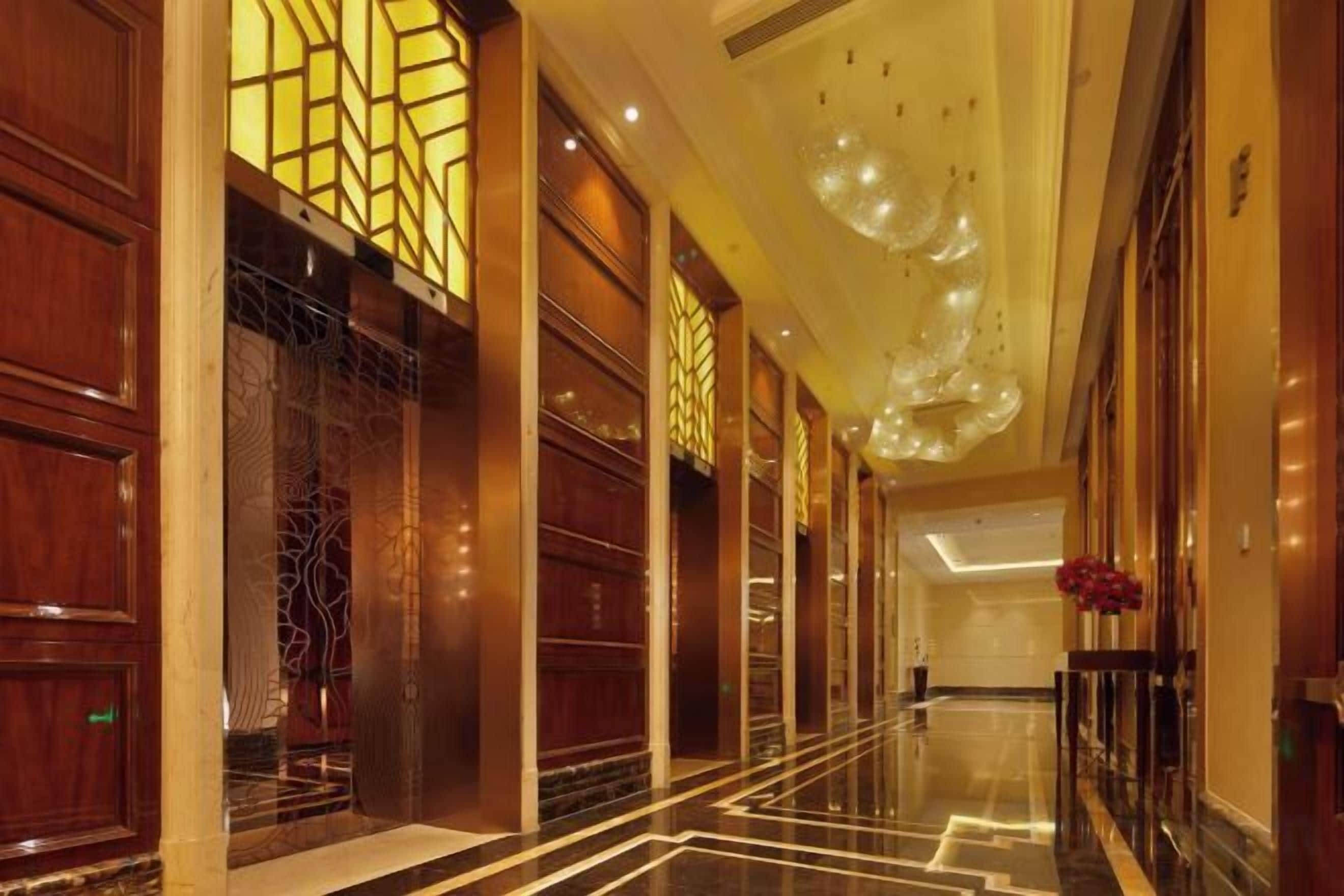 A hotel corridor with wooden paneling, a marble floor, and a decorative ceiling.