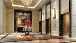 A luxurious lobby with a marble floor, a chandelier, a mirror, and a vase of flowers. - Sanyu Grand New Century Hotel (Wenzhou)