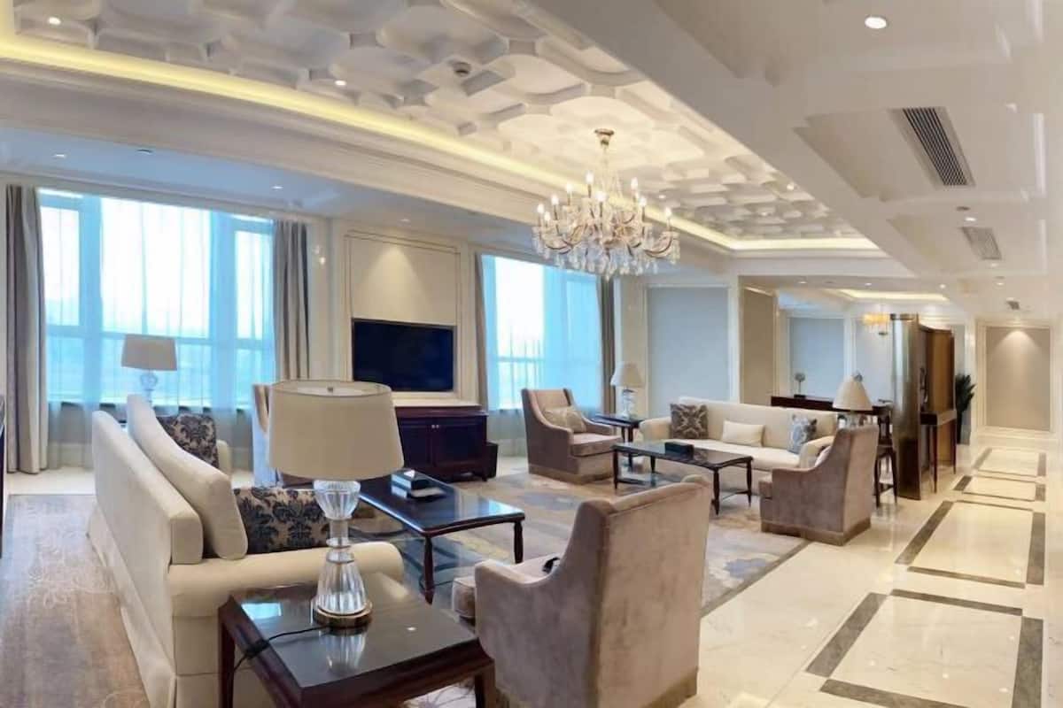A spacious living room with a sofa, armchairs, a coffee table, and a TV.
