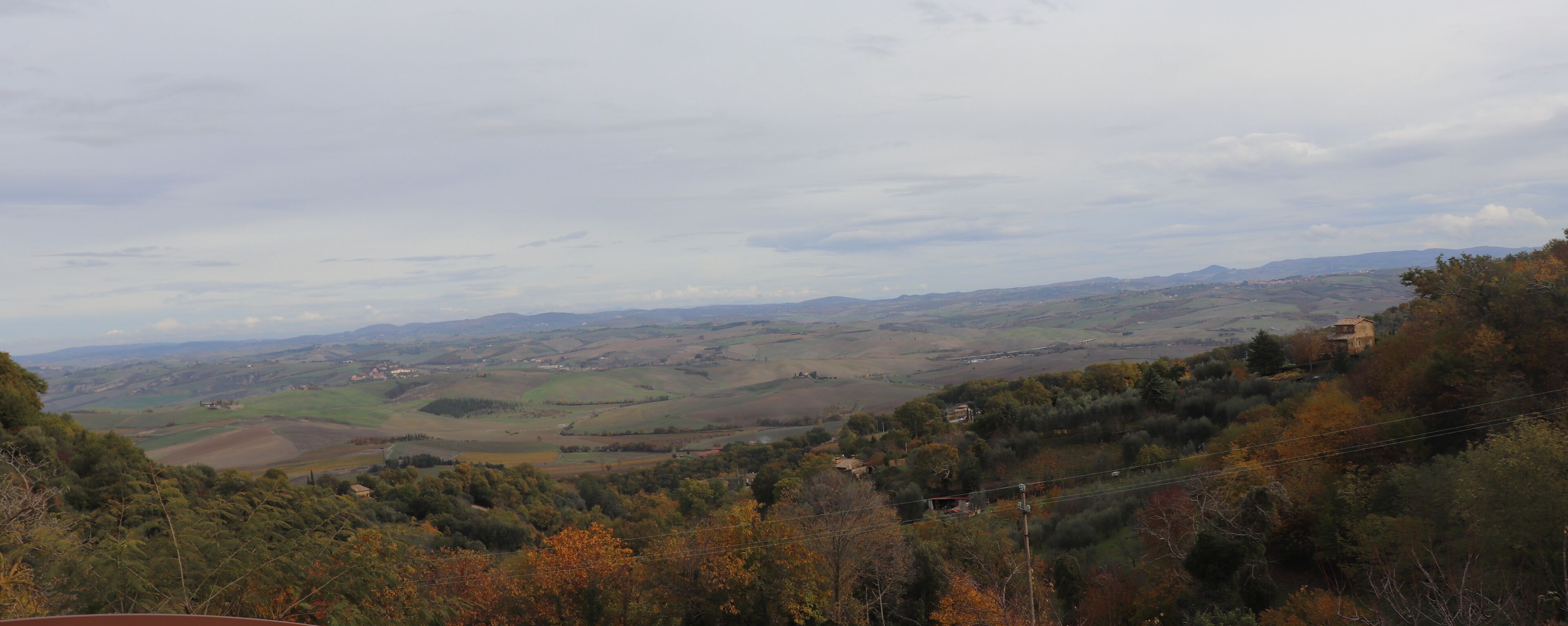 Vista panorámica de un paisaje montañoso con edificios y árboles dispersos.