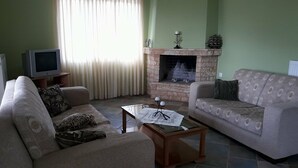 Uma sala de estar com dois sofás, uma mesa de centro, uma lareira e uma televisão.