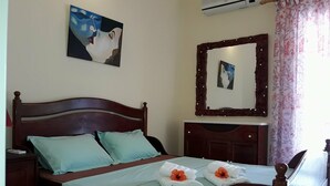 Uma cama bem arrumada com cabeceira de madeira, mesa de cabeceira, um espelho e um quadro na parede.