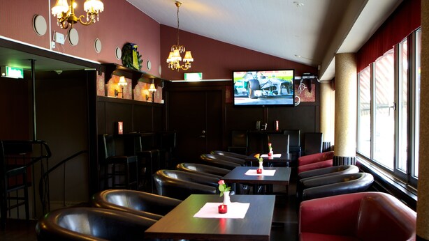 A restaurant with booths and tables, a TV screen, and a chandelier. - Stopet Hotell & Värdshus (Grangesberg)