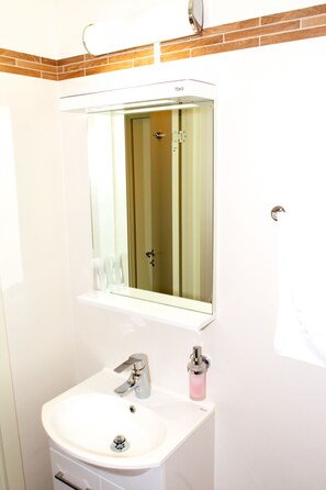 A bathroom with a white sink, a mirror, and a towel hanging on the wall. - Stopet Hotell & Värdshus (Grangesberg)