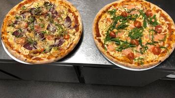 Two pizzas on a metallic surface.