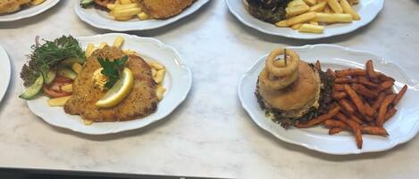A buffet with various dishes including fried fish, burgers, and fries.
