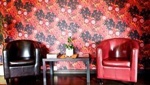 Two leather armchairs facing each other with a table between them, set against a floral wallpaper background. - Stopet Hotell & Värdshus (Grangesberg)