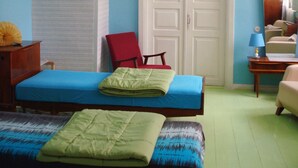 Ein Schlafzimmer mit einem Bett, einem roten Sessel, einem Schreibtisch mit Lampe und einem Kleiderschrank.