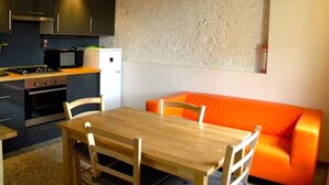Cocina compacta con zona de comedor, que incluye una mesa y sillas de madera, un refrigerador pequeño y un microondas.