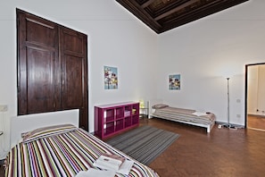 A bedroom with two beds, a wooden wardrobe, a pink cabinet, and two wall-mounted paintings. - Santi Apostoli (Florence)