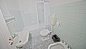 A bathroom with a toilet, bidet, sink, and shower. - Santi Apostoli (Florence)