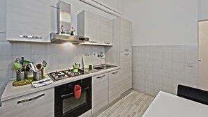 A modern kitchen with white cabinetry, a stainless steel sink, and a gas stove. - Santi Apostoli (Florence)