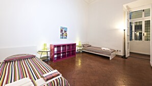 A room with a bed, a small table, a pink storage unit, and a window with a view. - Santi Apostoli (Florence)