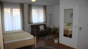 Ein Zimmer mit einem Bett, einem Sofa, einer Stehlampe und einem Blumentopf.