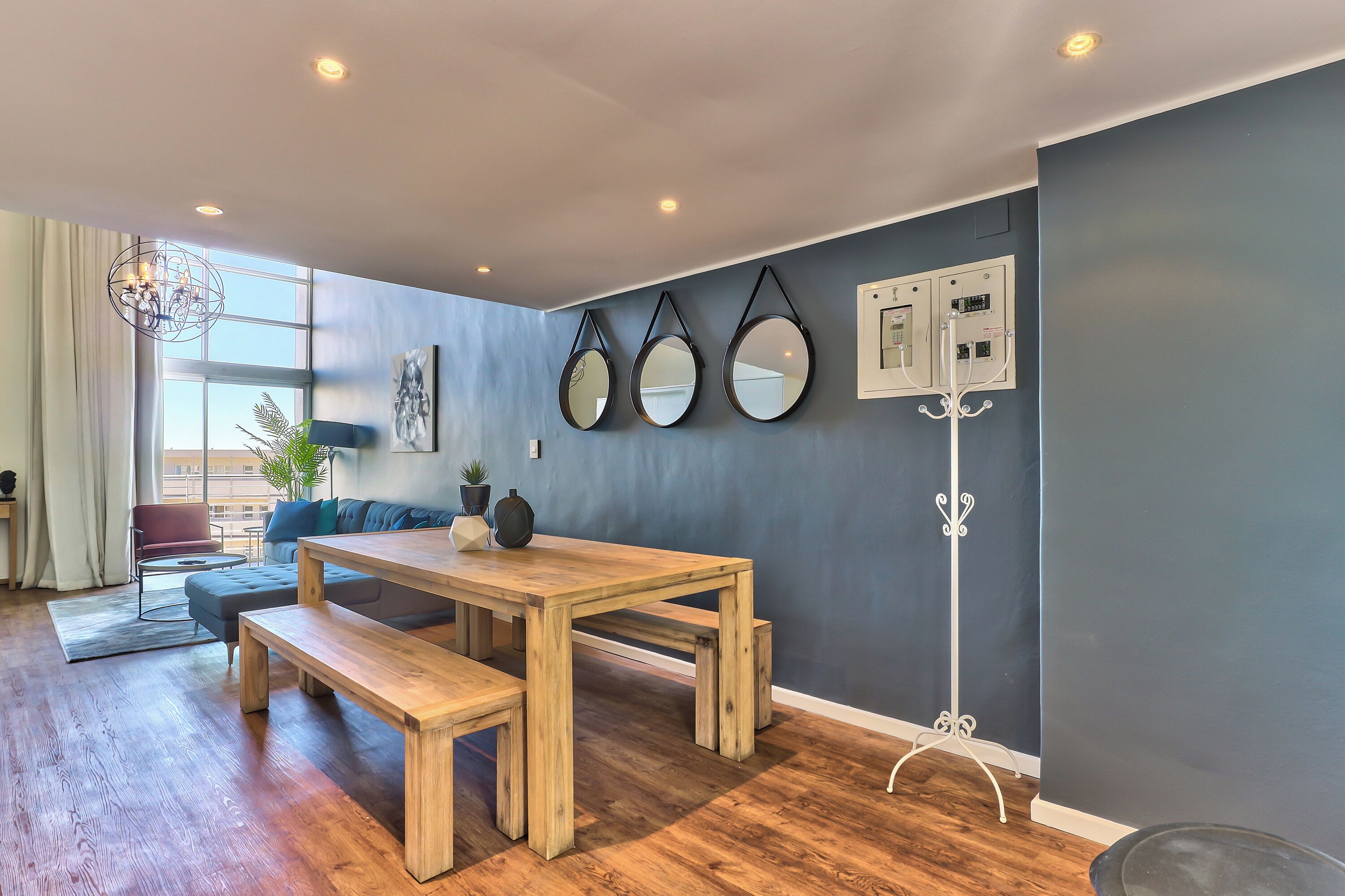 Een moderne woonkamer met een houten eettafel, banken, een bank en een groot raam.