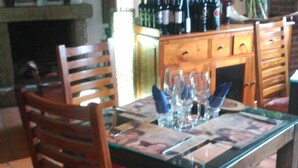 A dining table with chairs, a fireplace, and a wine rack in a rustic room. - La Picota (Valverde de la Vera)