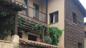 A two-story building with a stone facade, wooden balcony, and a metal railing. - La Picota (Valverde de la Vera)