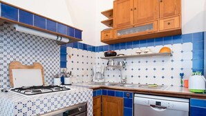 Una cocina con estufa a gas, horno, lavavajillas y baldosas de diseño azul y blanco.