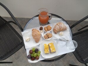 A table with a croissant, cookies, grapes, a glass of juice, and a pitcher of orange juice.
