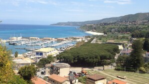 Un pueblo costero con un puerto deportivo, edificios y una playa.