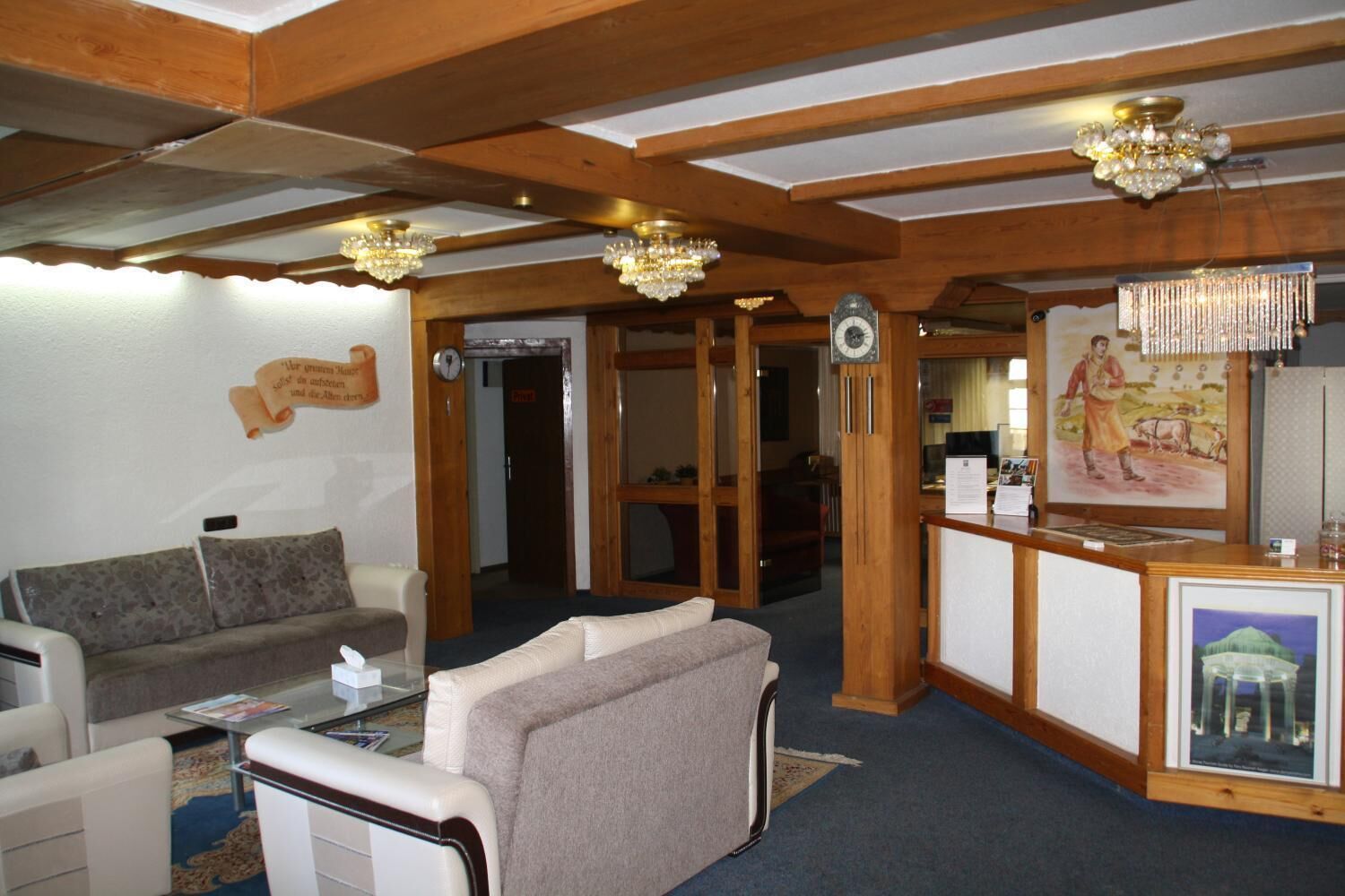 Eine Hotelhalle mit Rezeption, einer Uhr, einer Couch und einem Sessel.