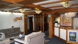 A hotel lobby with a reception desk, a clock, a couch, and a chair. - Hotel Hafez (Bad Salzuflen)