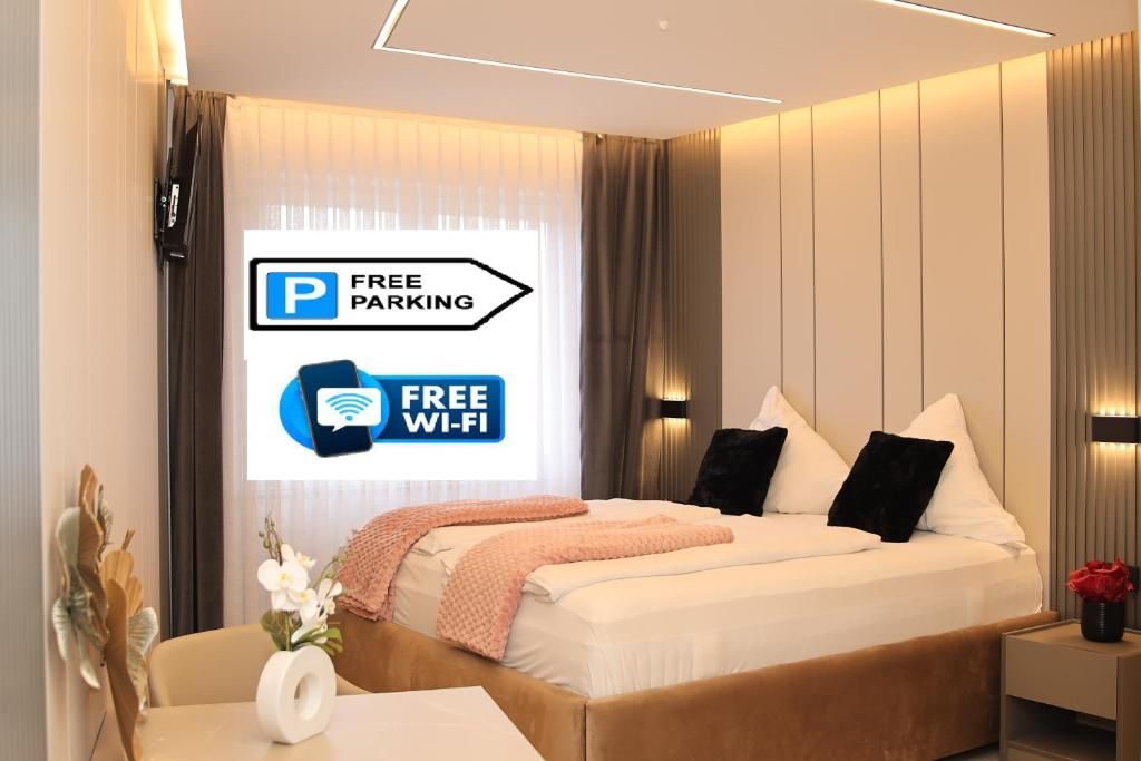 Ein modernes Hotelzimmer mit einem Bett, einem Schreibtisch und einem Nachttisch. Ein Schild weist auf kostenlose Parkplätze und kostenloses WLAN hin.