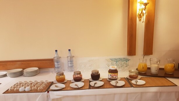 A breakfast buffet setup with plates, glasses, and various food items like Nutella and orange juice. - Hotel Hafez (Bad Salzuflen)