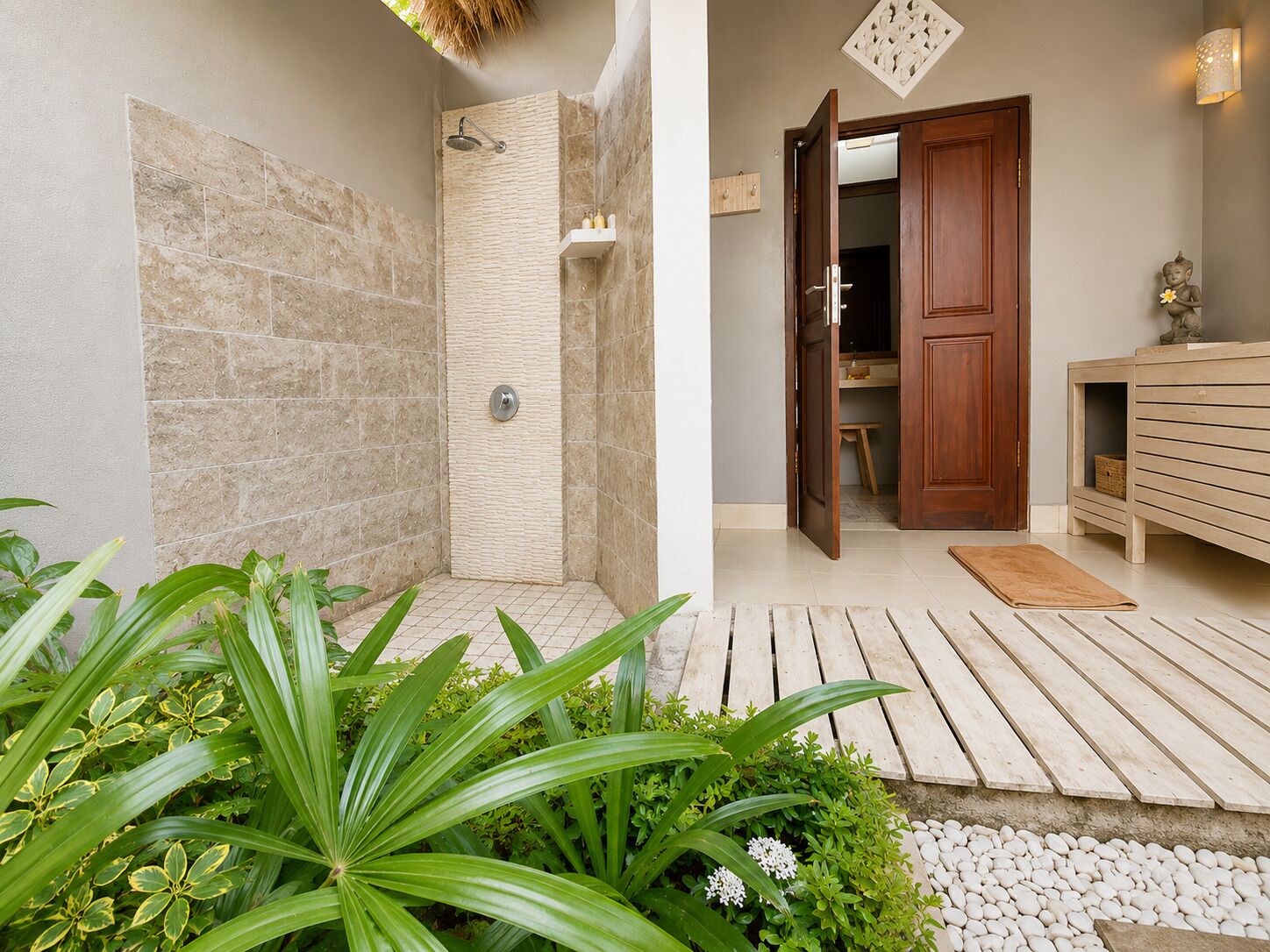 A bathroom with a shower, a wooden bench, and a small plant area.