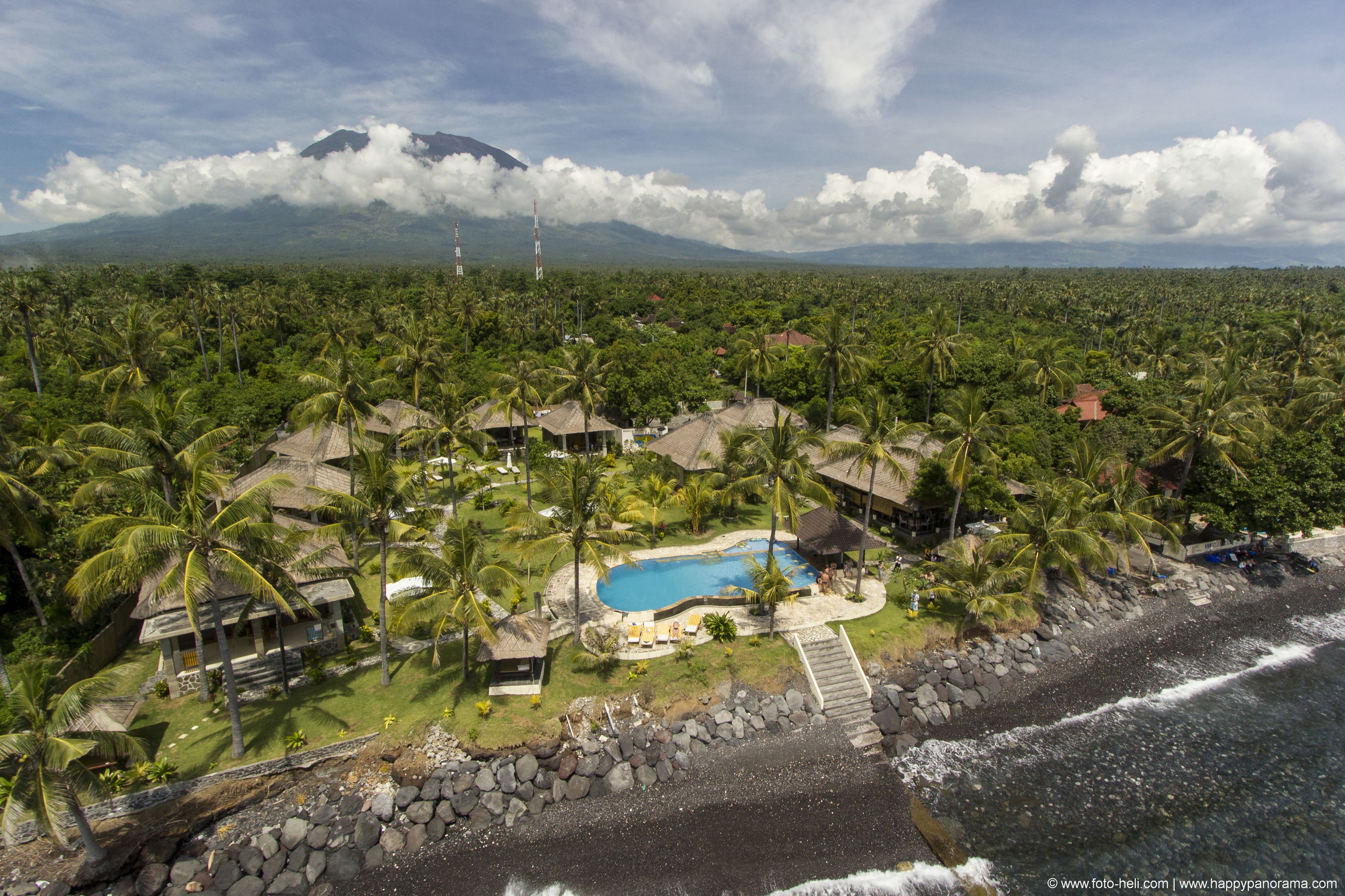 Un resort tropical con piscina, palmeras y una playa.