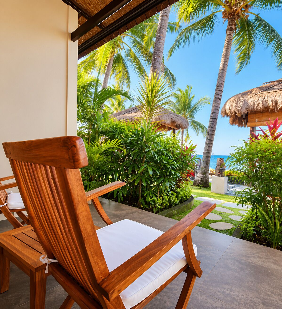 A wooden chair with a white cushion, a thatched-roof structure, and a view of palm trees and the ocean.