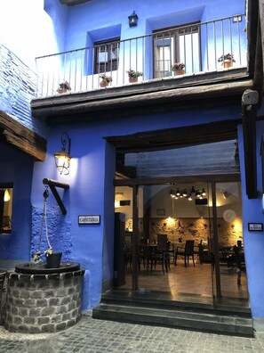 A building with a blue facade, a sign reading "CAFETERIA," and a stone well. - Hospederia Meson De La Dolores (Calatayud)