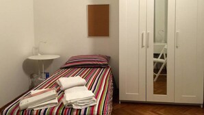 A bedroom with a bed, a bedside table, a white wardrobe, and a mirror. - Spadolini Apartment (Florence)