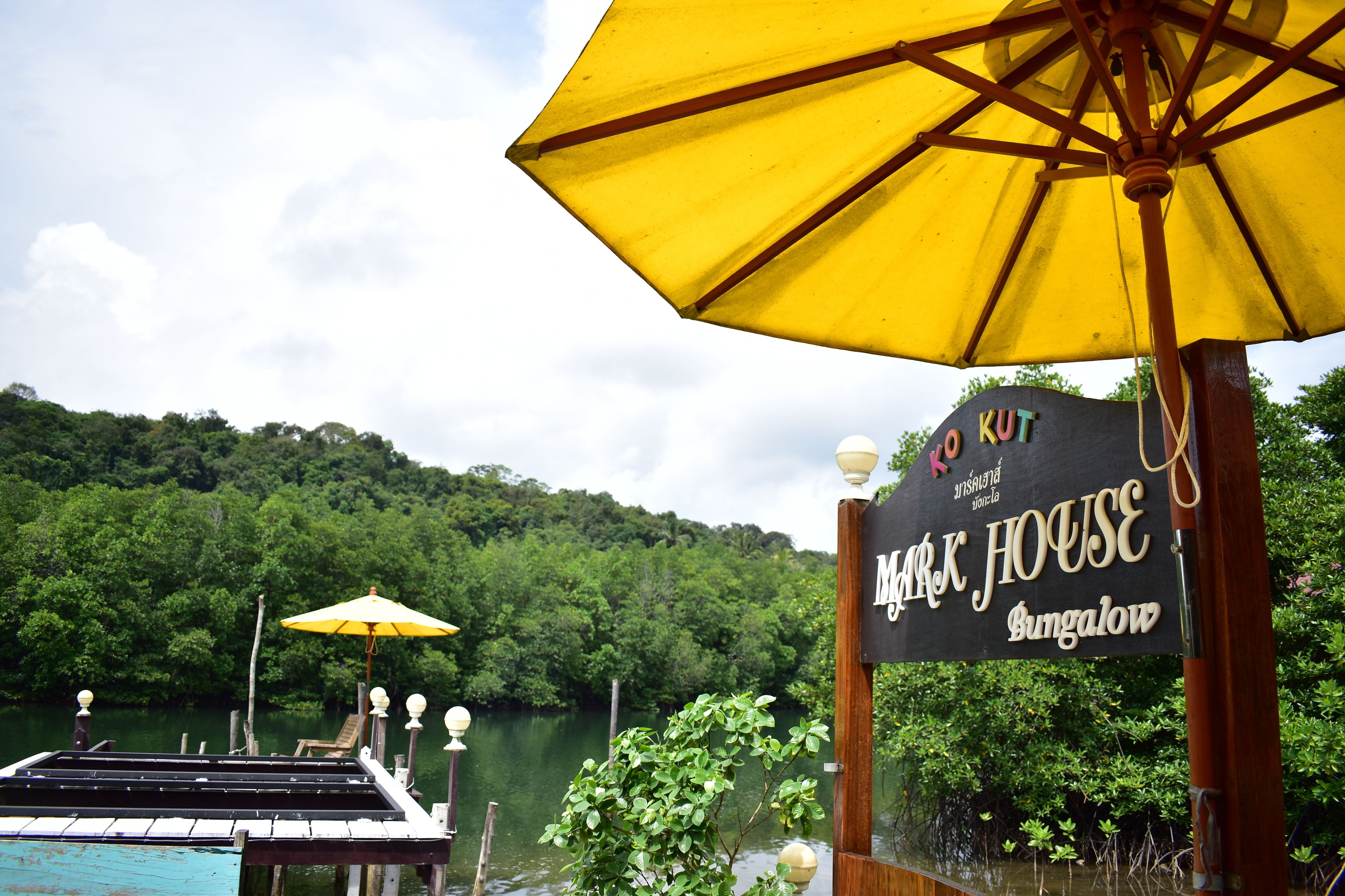 A sign for 'Dark House Bungalow' with a view of a lake and forested hills in the background.