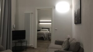 A hotel room with a bed, a TV, a sofa, and a painting on the wall. - Zannetti (Florence)